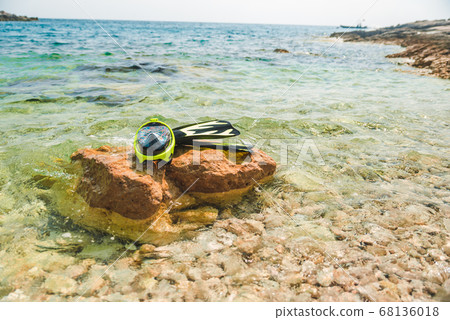 snorkeling mask with flippers at rock in sea water snorkeling mask with flippers at rock in sea water 68136018