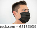 Black protective mask on the young guy's face, portrait 68136039