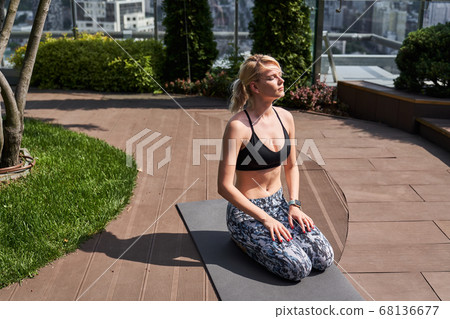 Calm lady sunbathing during her sports training outdoors Calm lady sunbathing during her sports training outdoors 68136677