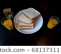 The bread and orange juice on the plate look delicious. 68137311