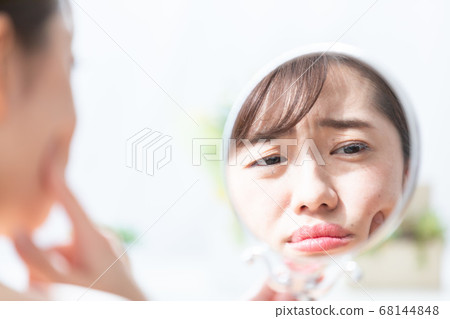 Woman looking in the mirror 68144848