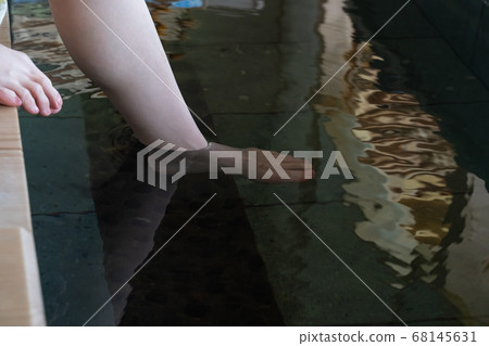 Female feet with one foot in footbath 68145631