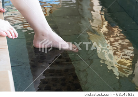 Female feet with one foot in the footbath 68145632