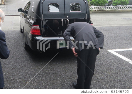 Ceremony staff bowing with casket on hearse 68146705