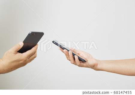 A male and female hands with phones opposite each A male and female hands with phones opposite each 68147455