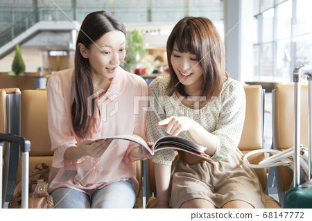 女人看著一本旅行書在機場 68147772