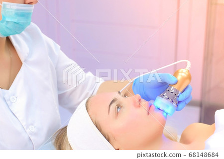 Cosmetologist doctor making phonophoresis procedure on woman face in clinic. 68148684
