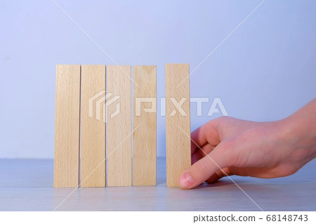 Man is building wooden blocks in row as fence, hand closeup view. 68148743