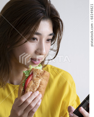 一個女人一邊吃飯一邊看一部智能手機 68149821