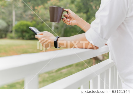 Coffee break businessman holding coffee and looking at smart phone on balcony. 68151544