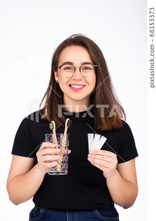 Choosing between brushing your teeth and chewing gum concept. Woman offering to choose between toothbrush and chewing gum Choosing between brushing your teeth and chewing gum concept. Woman offering to choose between toothbrush and chewing gum 68153373
