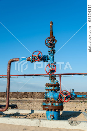 Petroleum well wellhead equipment. Hand valve with handwheel on the flow line. Oilfield site. Oil, gas industry concept. Industrial site background. Production oil. Multiple check valve gate armature. Petroleum well wellhead equipment. Hand valve with handwheel on the flow line. Oilfield site. Oil, gas industry concept. Industrial site background. Production oil. Multiple check valve gate armature. 68154315