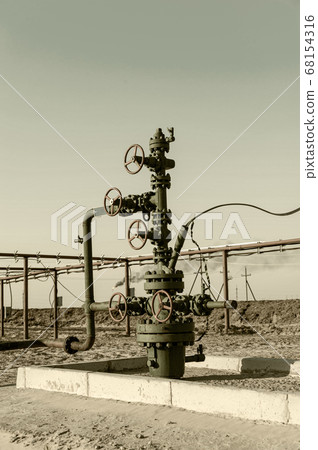 Petroleum well wellhead equipment. Hand valve with handwheel on the flow line. Oilfield site. Oil, gas industry concept. Industrial site background. Production oil. Multiple check valve gate armature. Petroleum well wellhead equipment. Hand valve with handwheel on the flow line. Oilfield site. Oil, gas industry concept. Industrial site background. Production oil. Multiple check valve gate armature. 68154316