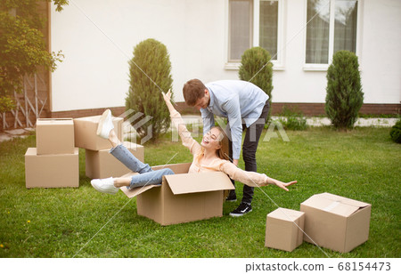 Young family enjoying moving day, being silly together in front yard of their new home Young family enjoying moving day, being silly together in front yard of their new home 68154473