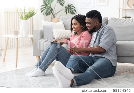 Happy Black Couple Using Laptop At Home For Online Shopping, Ordering Goods Happy Black Couple Using Laptop At Home For Online Shopping, Ordering Goods 68154545
