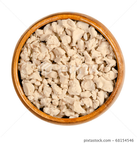Crumbled fresh bakers yeast in a wooden bowl. Compressed fresh yeast, crushed with fingers, used in baking as a leavening agent. Saccharomyces cerevisiae. Close-up, from above, over white, food photo. Crumbled fresh bakers yeast in a wooden bowl. Compressed fresh yeast, crushed with fingers, used in baking as a leavening agent. Saccharomyces cerevisiae. Close-up, from above, over white, food photo. 68154546