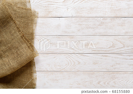 Copy space on a rustic textured wood tabletop painted with white paint and burlap of natural color. 68155880