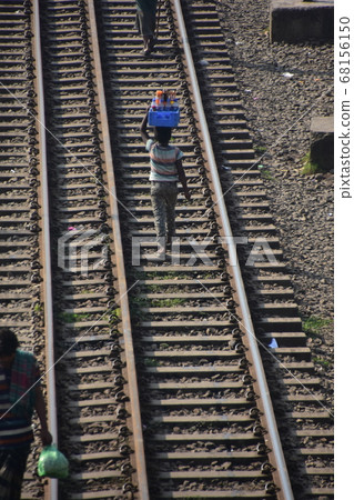 Kompurpur station in Dhaka, Bangladesh A boy selling drinks walking along the track, carrying a basket on his head Kompurpur station in Dhaka, Bangladesh A boy selling drinks walking along the track, carrying a basket on his head 68156150