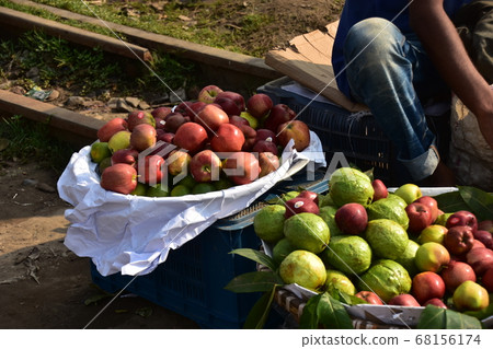 Kommrapur station in Dhaka, Bangladesh A man selling fruits along the railroad track A lot of apples in a basket 68156174