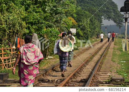 People walking along the tracks of Joydpur Station in the suburbs of Dhaka, Bangladesh, holding mulberry and colander and heading for agricultural work People walking along the tracks of Joydpur Station in the suburbs of Dhaka, Bangladesh, holding mulberry and colander and heading for agricultural work 68156214