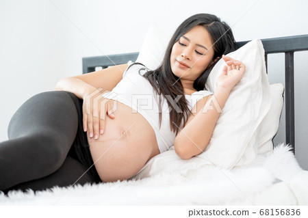Beautiful Asian pregnant woman lie with relax position and use one hand touch her belly Beautiful Asian pregnant woman lie with relax position and use one hand touch her belly 68156836