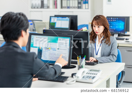 Employees operating a computer in the office 68156912