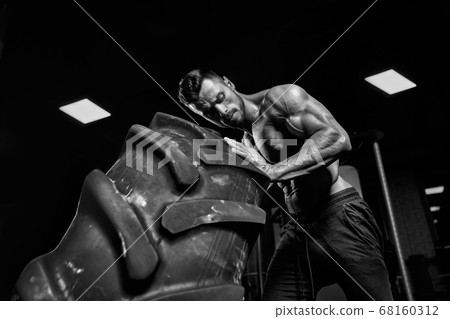 Monochrome close up of man moving tire. 68160312