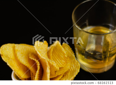 glass of whiskey with ice cubes and salty snacks 68161513