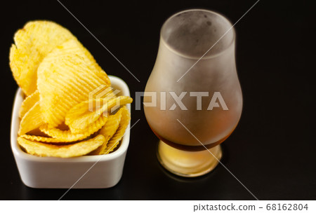 glass of whiskey with ice cubes and salty snacks 68162804