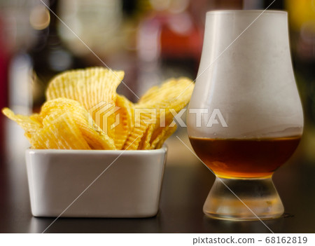 glass of whiskey with ice cubes and salty snacks glass of whiskey with ice cubes and salty snacks 68162819