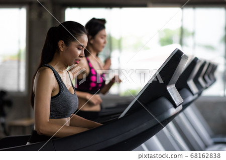 Fit people run on treadmills machine in gym 68162838