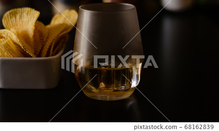 glass of whiskey with ice cubes and salty snacks 68162839