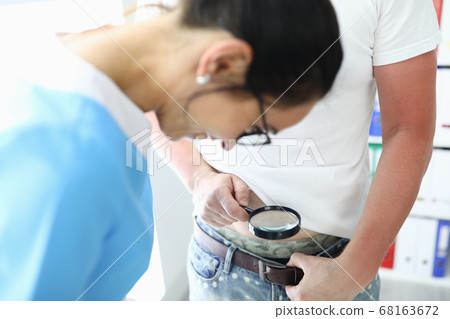 Patient holds magnifying glass over pants of medical worker smiling looks. Patient holds magnifying glass over pants of medical worker smiling looks. 68163672