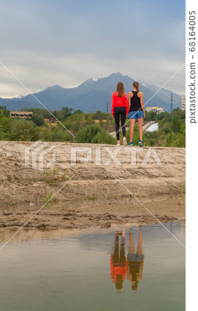 Two beautiful girls came to the city park in new sportswear to go jogging. 68164005
