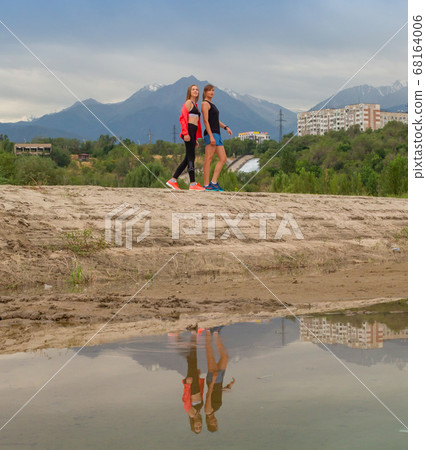 Two beautiful girls came to the city park in new sportswear to go jogging. 68164006