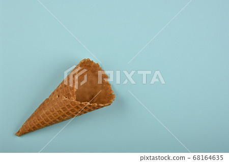 One empty wafer ice cream cone over blue One empty wafer ice cream cone over blue 68164635