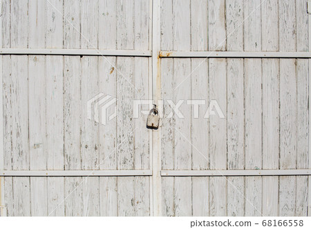 Old wooden gate closed with a padlock. White paint will peel off 68166558