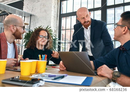 Beautiful business people are using gadgets, talking and smiling during the conference in office. Selective focus 68168236