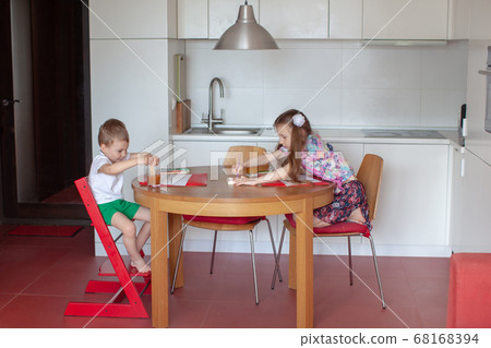 Seven year old girl and three year old boy paint. Modern kitchen interior.  68168394