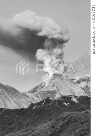 Volcanic landscape, beautiful view of erupting volcano, plume of steam, gas, ashes from crater active volcano. Eurasia, Russian Far East. Black and white image. 68168733