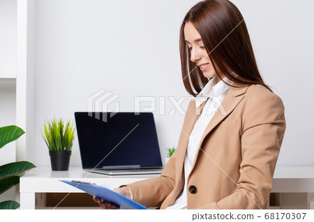 Young beautiful businesswoman working on laptop in bright modern office Young beautiful businesswoman working on laptop in bright modern office 68170307