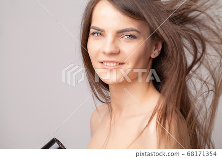 Beautiful smiling woman drying her long hair with dryer Beautiful smiling woman drying her long hair with dryer 68171354