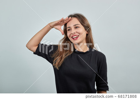 woman holding the palm of her hand on her forehead, gazing into the distance 68171808