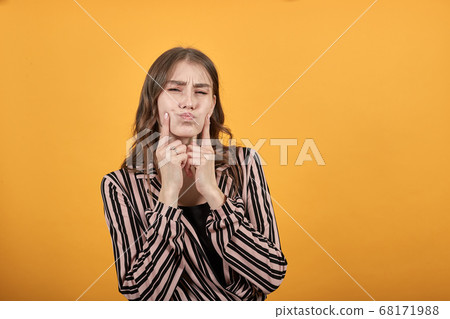 Dissatisfied Girl Touches Her Fingers To Cheeks, Outraged Dissatisfied Girl Touches Her Fingers To Cheeks, Outraged 68171988