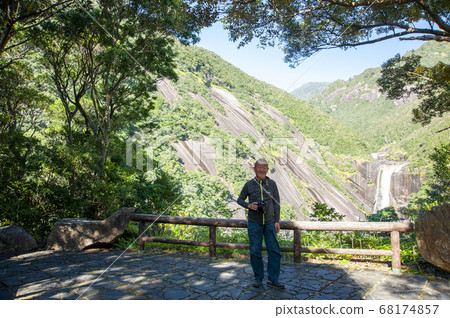 Senior man enjoying a photo shoot at Yakushima Chihiro Falls sightseeing 68174857