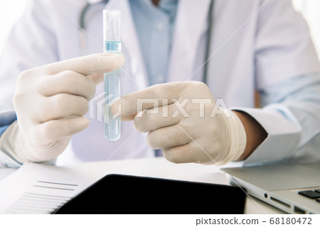 Scientist or tech holds liquid biological sample in gloved hands in the laboratory. Scientist or tech holds liquid biological sample in gloved hands in the laboratory. 68180472