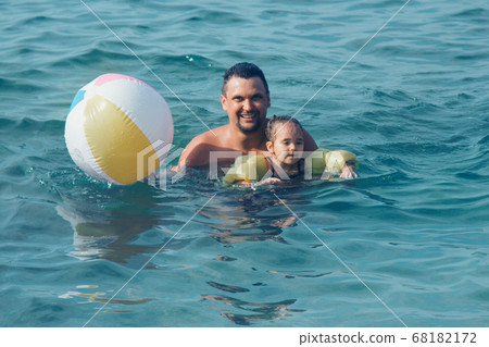 A young father and daughter swim in the sea. swimming training. ball game A young father and daughter swim in the sea. swimming training. ball game 68182172