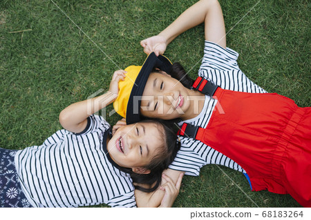 Flat lay - two thai little girl laying on grass Flat lay - two thai little girl laying on grass 68183264