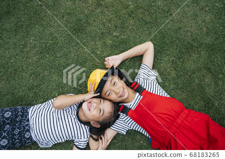 Flat lay - two thai little girl laying on grass Flat lay - two thai little girl laying on grass 68183265