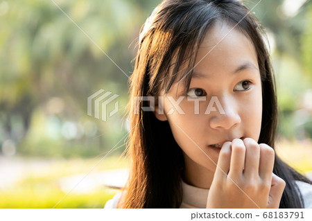 Stressed worried child girl bites finger nails,female people with nail biting,feel anxious,woman with hand on mouth biting her nails,risk of bringing germs into the body,anxiety,psychiatric problems Stressed worried child girl bites finger nails,female people with nail biting,feel anxious,woman with hand on mouth biting her nails,risk of bringing germs into the body,anxiety,psychiatric problems 68183791